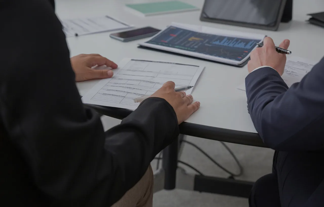 Dos personas sentadas revisando unos papeles